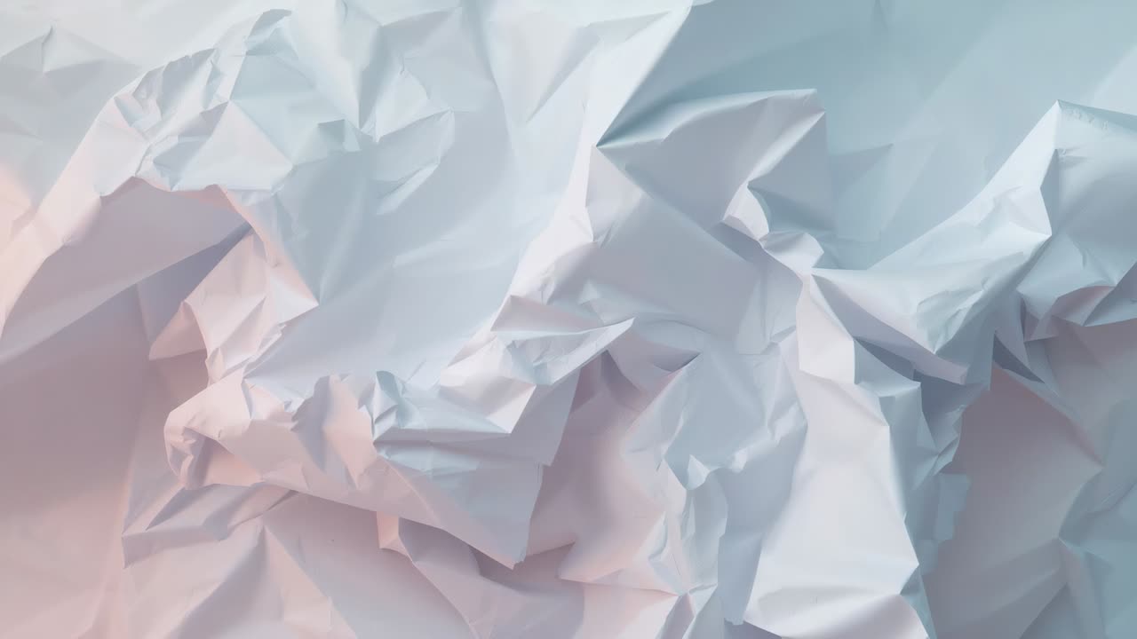 Panning camera revealing crumpled white sheet at studio table, showing folds with blue-pink light