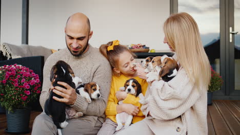 familia feliz con un niño y una mascota se sienta en la veranda de la casa de nieve. retrato de una familia feliz