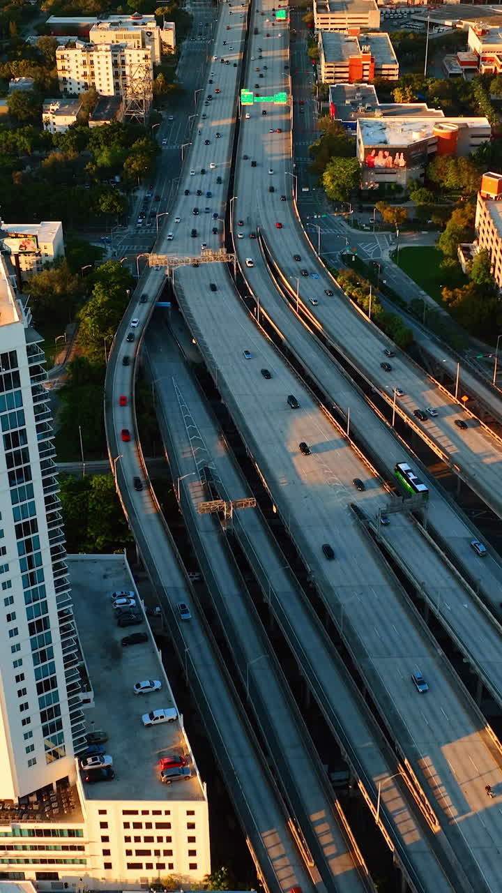 Lively multi-lane speedway with cars running by. Highway in downtown of Miami, Florida, USA at sunset. Top view. Vertical video