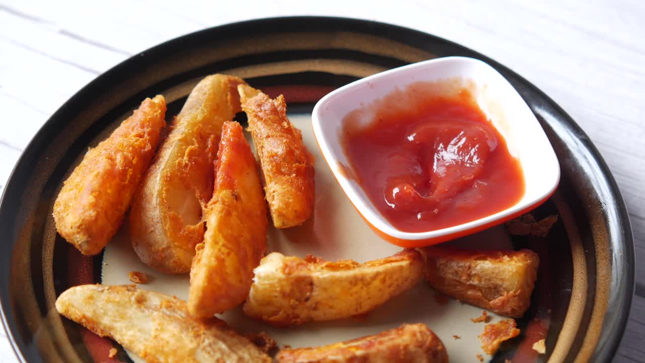 Hand Dipping Potato Wedges in Ketchup