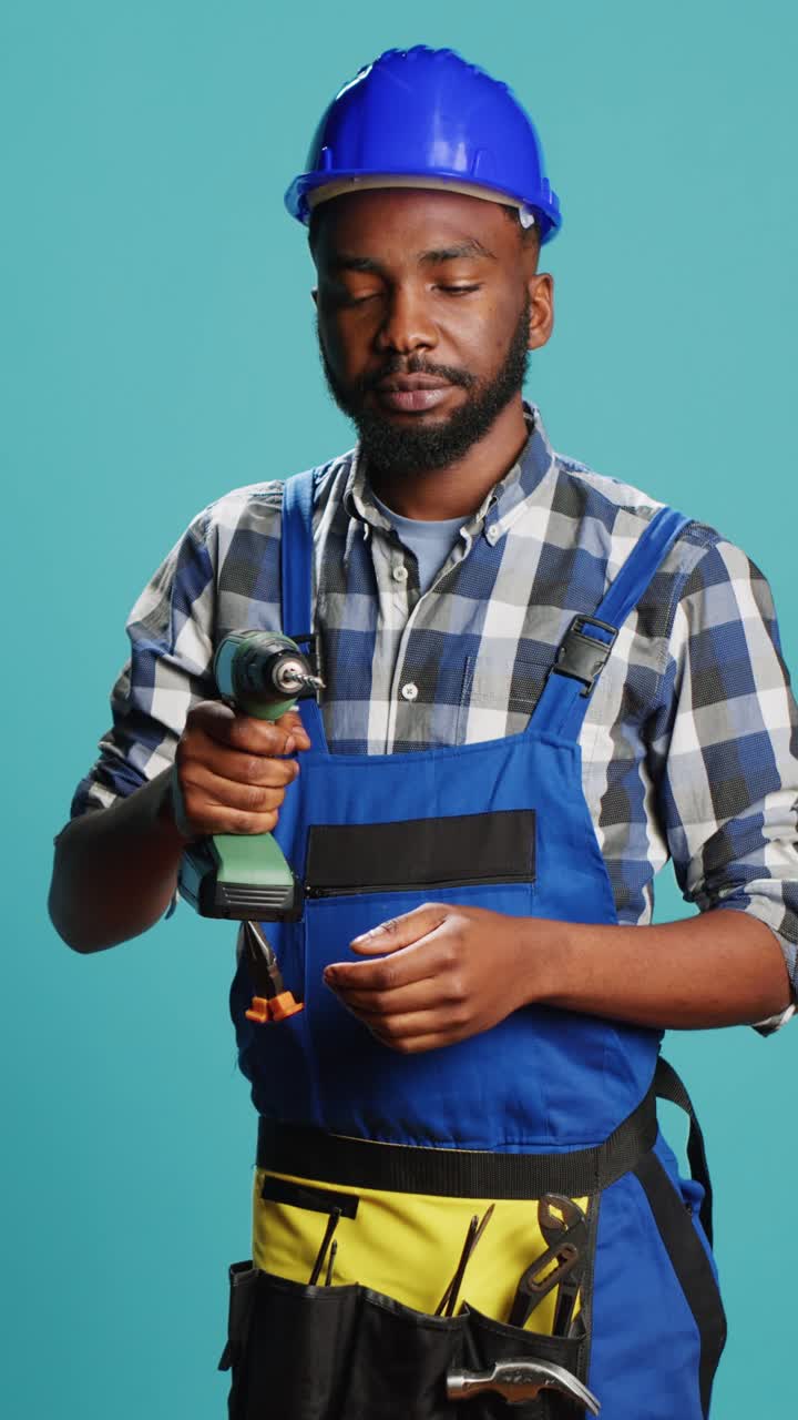 Vertical video: Young repairman using power drill gun on wall