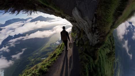 un excursionista en un camino de montaña por encima de las nubes