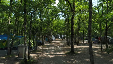 Drohnenansicht,-Die-Zwischen-Bäumen-Und-Zelten-Auf-Einem-Campingplatz-Fliegt.-Frankreich-Sonniger-Tag.