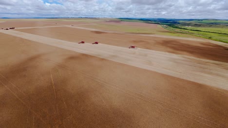 aerial view of combine harvesters working on a vast field lof of soybean in a rural area of são joão da aliança, goiás, brazil, during a cloudy day of summer