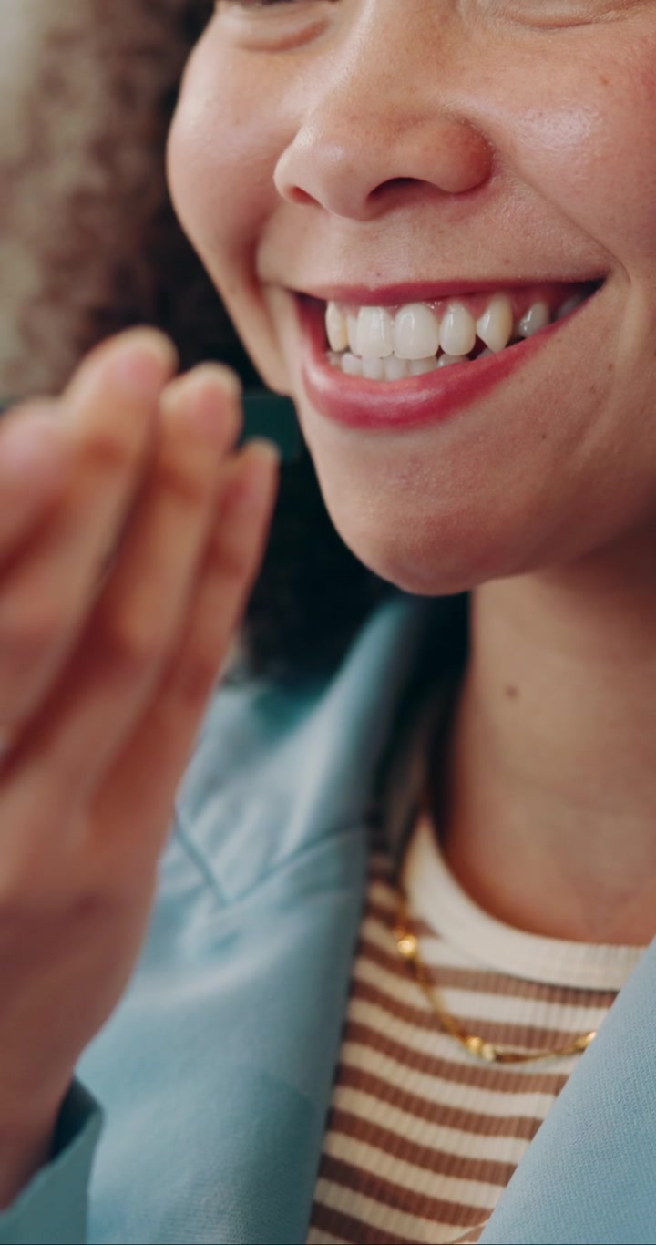 Primo piano di una donna sorridente che registra un messaggio vocale sul suo smartphone
