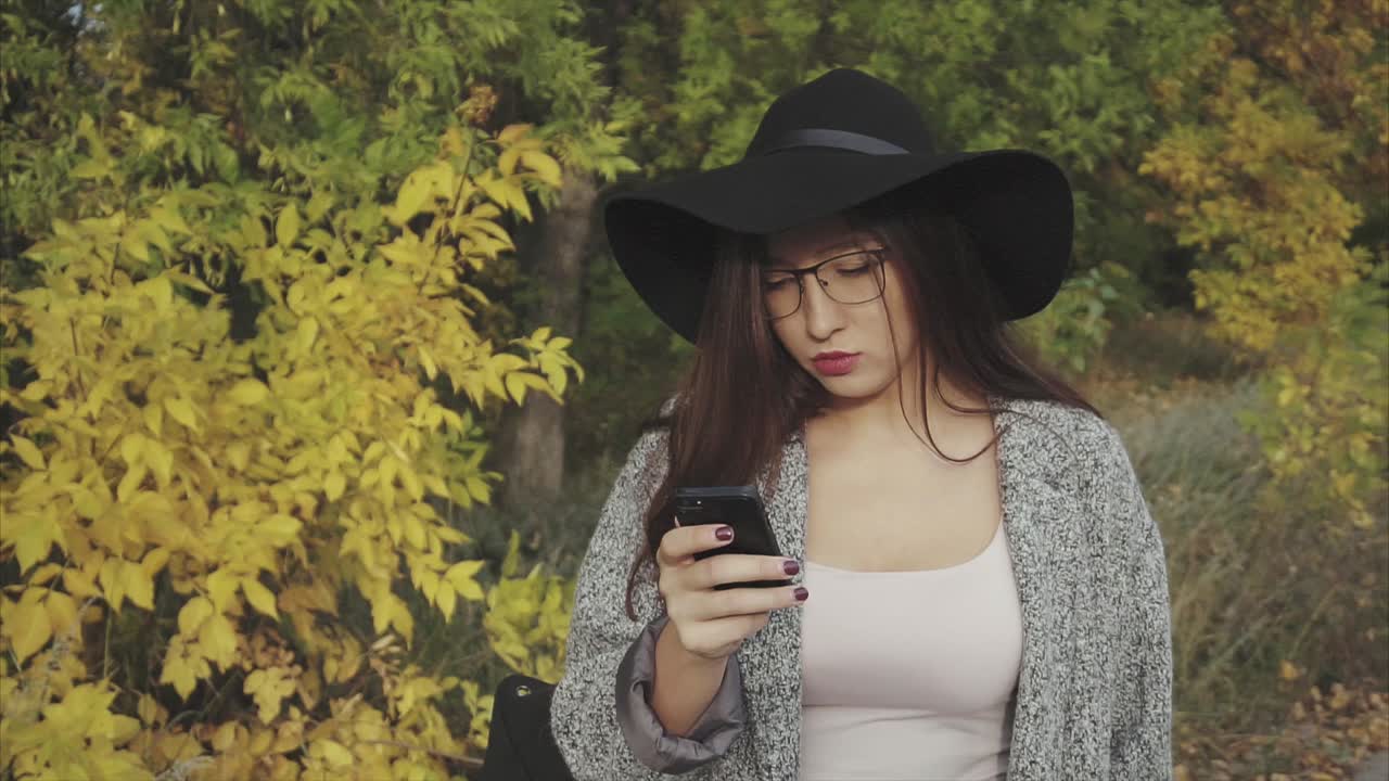 Woman using phone in an autumn park