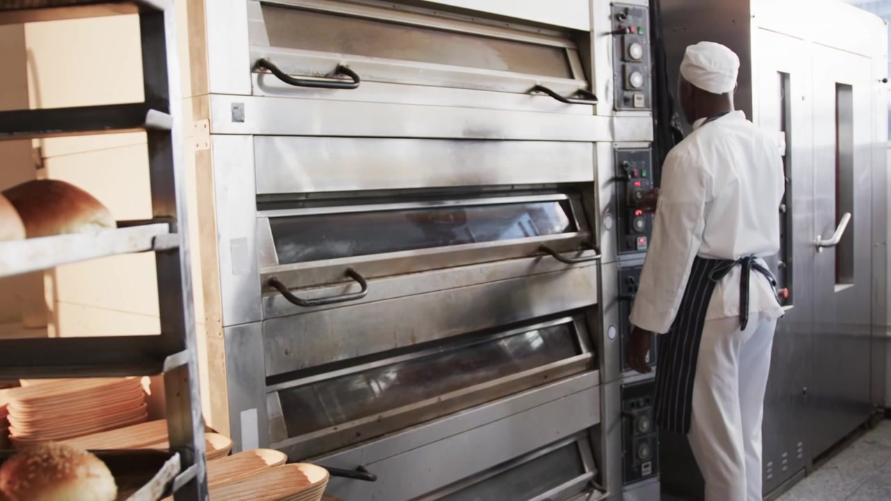 Câmera recuando, sobreposições de código aparecendo sobre o forno, estante de padaria, padeiro ajustando o forno verificando o cozimento
