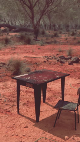 una mesa y una silla en el medio de un desierto de tierra roja