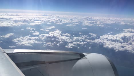 turbine view from an airplane flying above the clouds and the snowed mountains of alps in europe