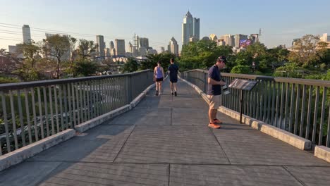 a jogger passes a pedestrian on a sunny city bridge.