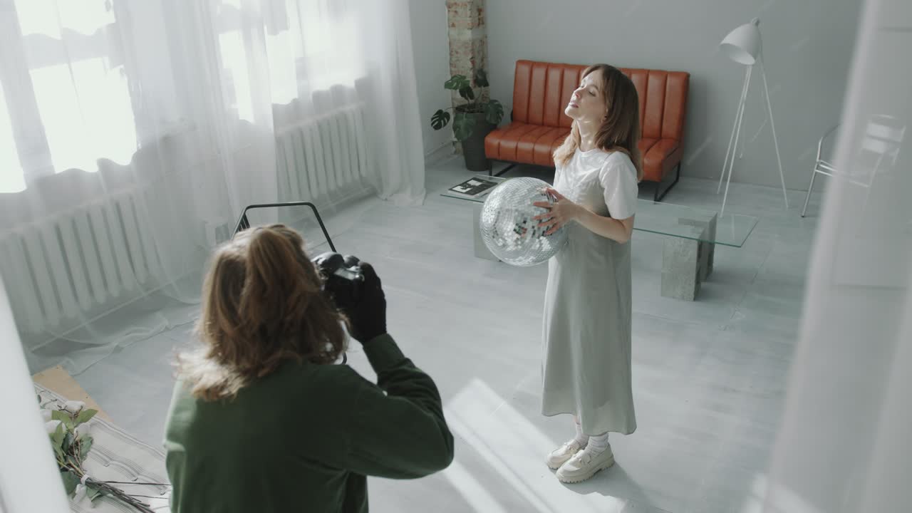 Photographer Capturing Images of Female Model Holding Disco Ball in Studio