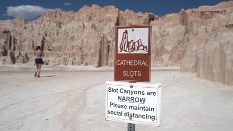 signs at cathedral gorge state park ion plateau n front of narrow slots canyons and female visitor passing by, close up