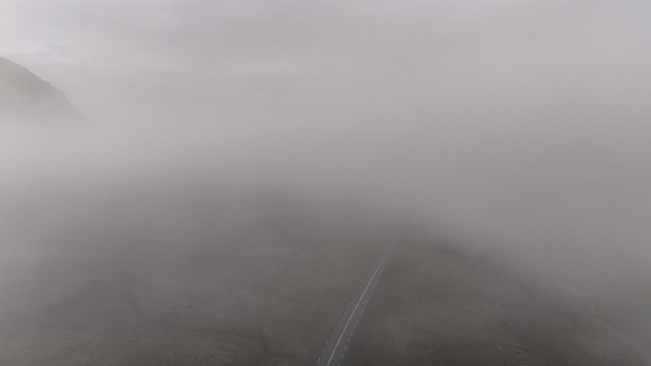 Misty mountain slopes and small waterfalls overlook Berufjörður as drifting clouds slide across the rugged Icelandic landscape