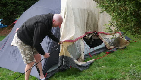 a man pitching a tent and dropping a tent pole