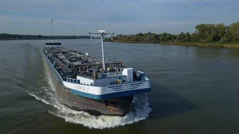 aerial slide and pan footage of front end of ship tanker transporting liquid goods on river route