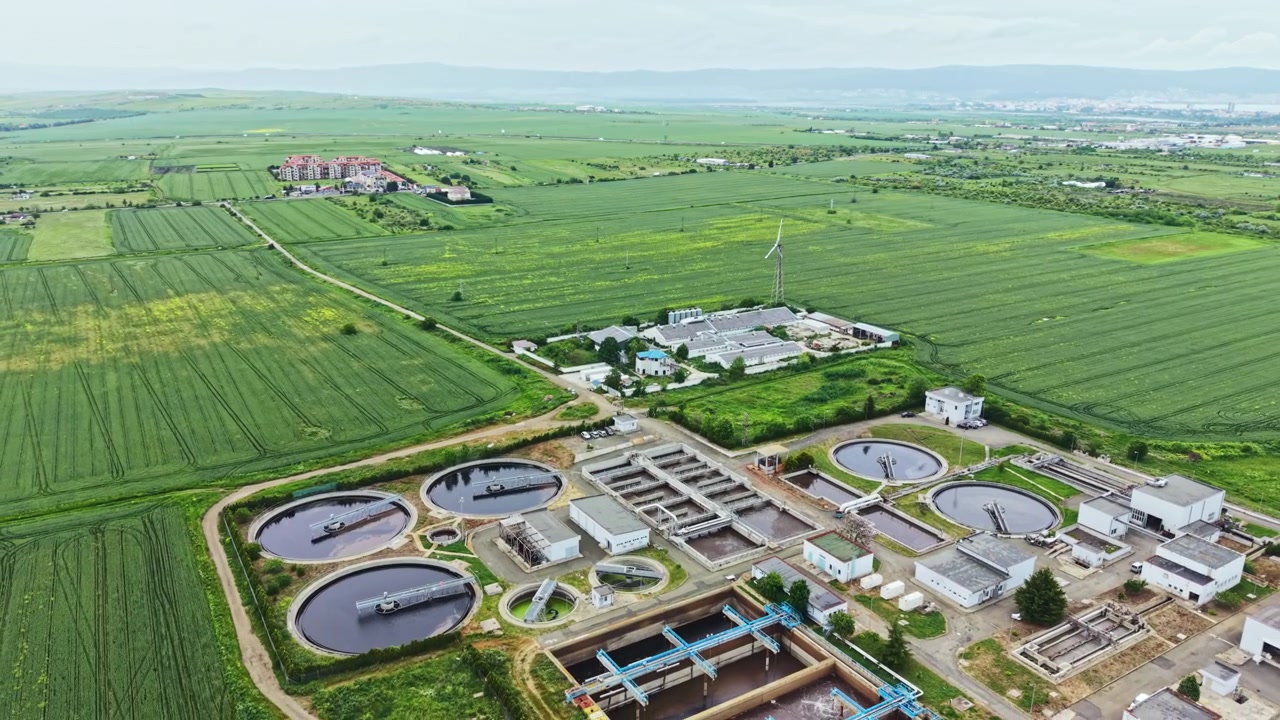 Treatment plant adjacent to cultivated fields and irrigation channels. Remote monitored water purification site integrated with lush crop fields and rural infrastructure