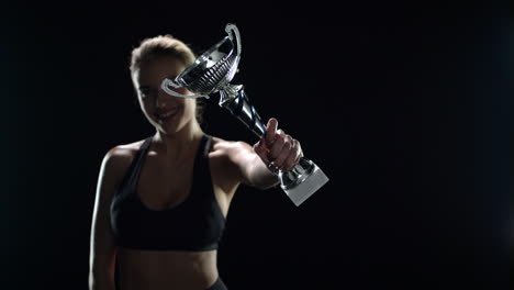 Happy-woman-champion-holding-trophy-cup-in-studio.-Sport-woman-winner