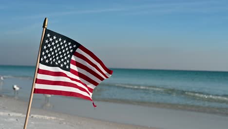 american flag on white sand beach on a bright sunny day