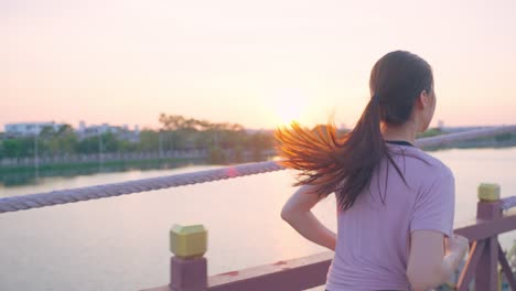 woman running at sunset on a bridge