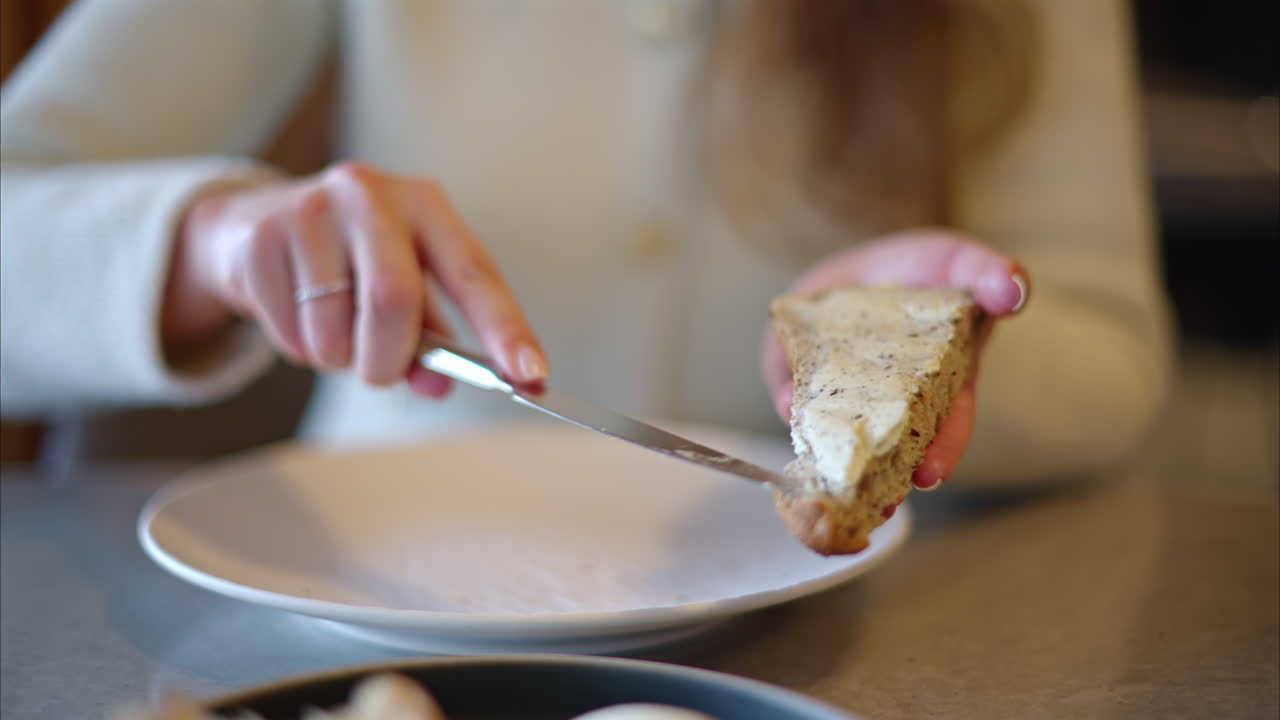 Woman spreading cream cheese on whole wheat bread