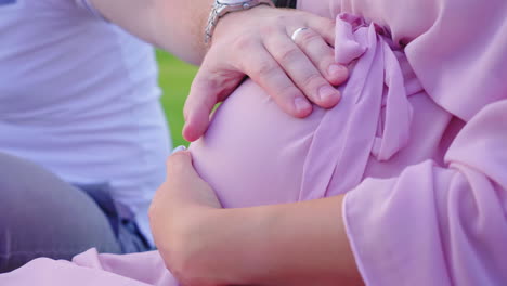 hands of a young married couple on the big belly of a pregnant woman