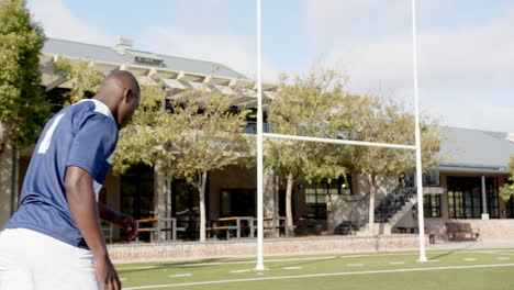 playing rugby, african american man in jersey number 4 kicking ball through goalposts, on field