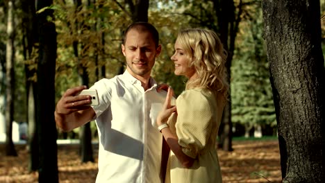 smiling couple making selfie in autumn park
