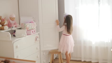 a little girl is choosing a dress in the wardrobe.