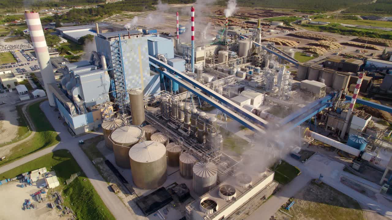 Aerial view of a large industrial complex with smoke and steam rising from chimneys