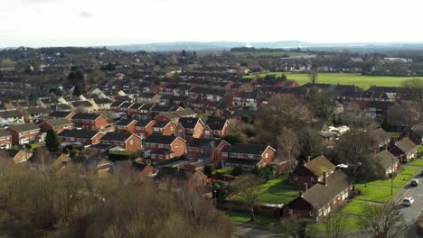 Rural-British-townhouse-neighbourhood-homes-with-green-space-aerial-view-across-to-Snowdonia-mountain-skyline,-pull-back-orbit-right