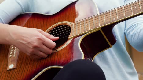 Eine-Nahaufnahme-Einer-Jungen-Frau-Spielt-Gitarre-In-Der-Nähe-Eines-Alten-Hauses