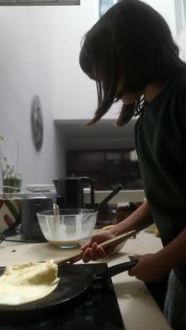 child cooking pancakes in a kitchen