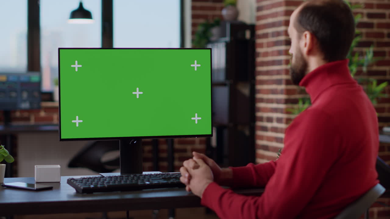 Male employee working with green screen on monitor