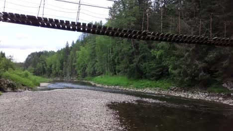 wooden suspension bridge over a river in a forest