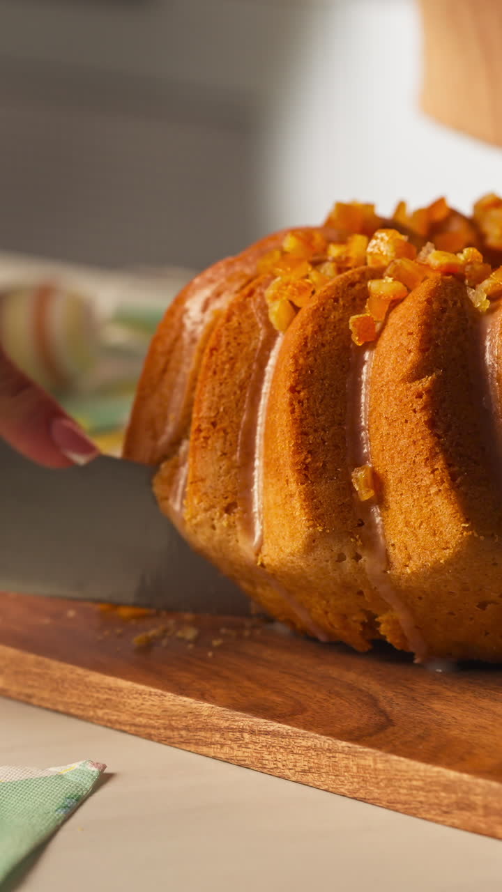 Slicing Bundt Cake With Glaze And Chopped Candied Fruit Topping. - vertical, closeup shot