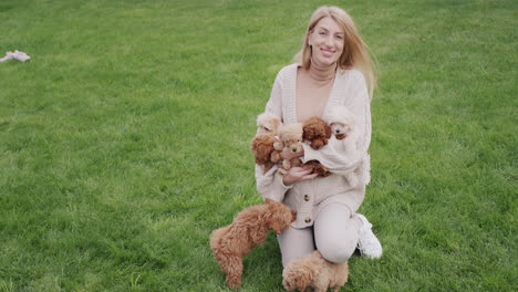 attractive pregnant woman playing with several puppies on the lawn