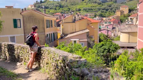 young woman walking through picturesque streets of cinque terre, italy – rear view in colorful mediterranean village