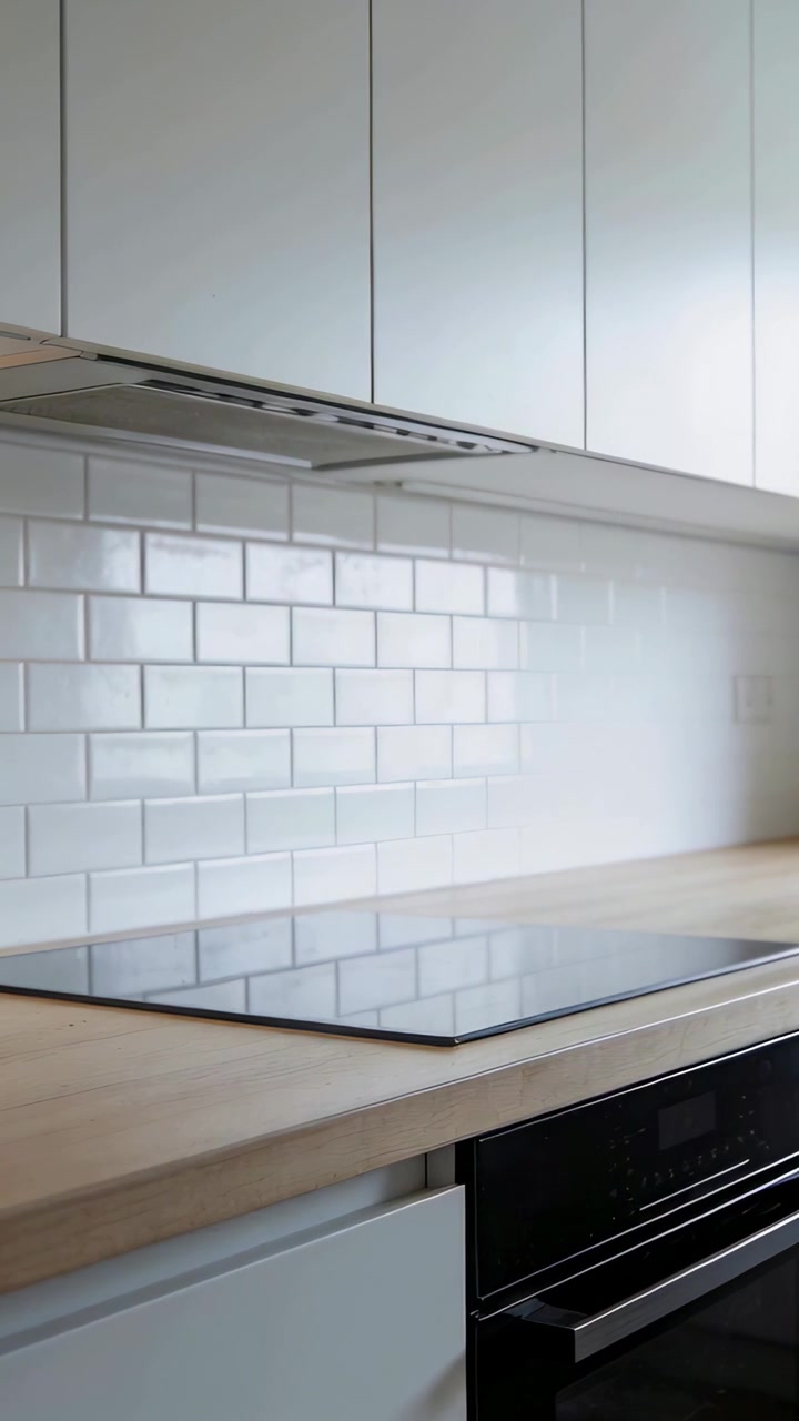 Vertical video: Panning camera revealing black cooktop in kitchen, highlighting glossy subway tiles