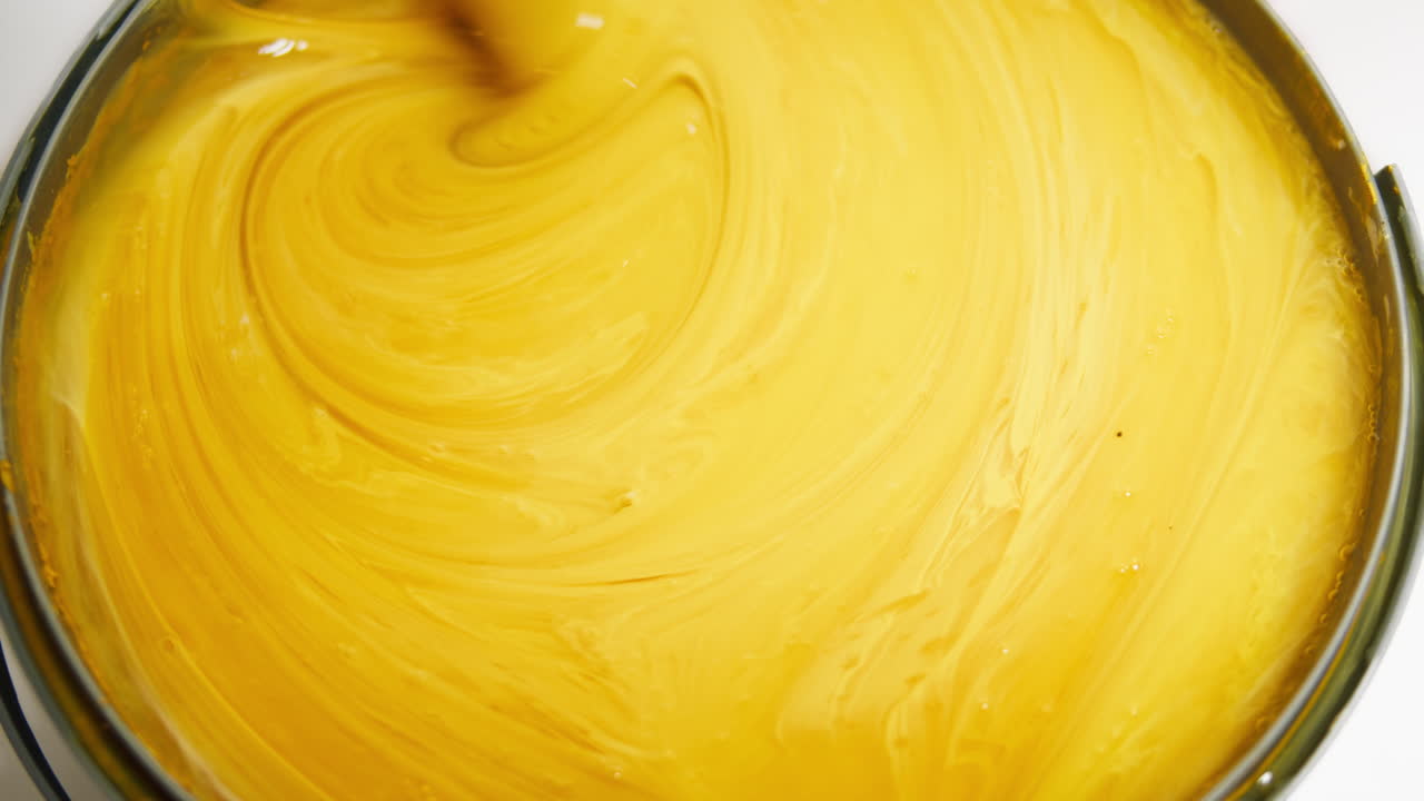 Close-up of Yellow Paint Being Stirred in a Container
