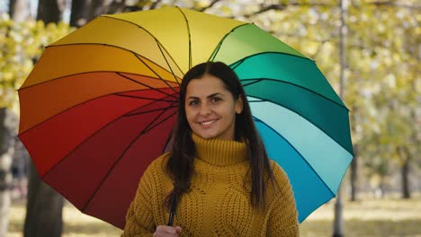 portrait of caucasian woman with colourful umbrella at park