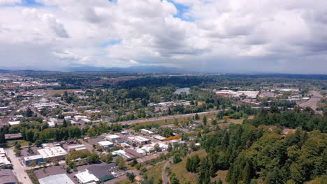 Cloudy-Summer-Sky-Over-City-Skyline-With-Lush-Trees-In-Eugene,-Oregon---aerial