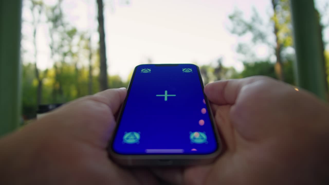 Woman hand holding phone with chroma key screen in front of laptop outdoor. Smartphone with green screen close-up
