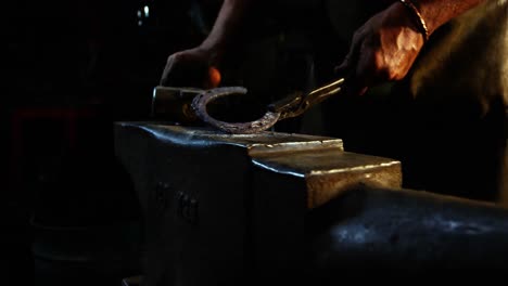 Mid-section-of-blacksmith-working-on-a-horseshoe