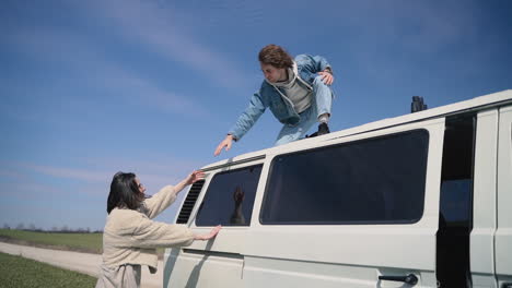 young boy helps his girl friend onto the roof of the caravan