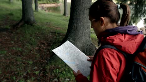 slow motion of a young tourist woman searching for the way on the map and the compass.