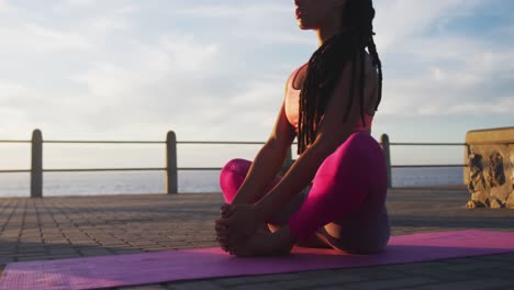 Afroamerikanische-Frau-In-Sportkleidung-Macht-Yoga-Auf-Der-Promenade-Am-Meer