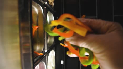 Topping-pizza-with-bell-peppers-slices-Vertical