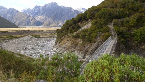 bridge over mountain stream in red tarns track, mount cook, new zealand - wide shot