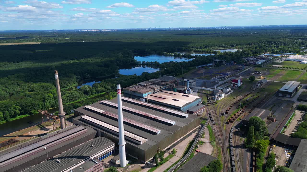 Hennigsdorf Steel Mill showcasing its industrial operations, chimneys, vast railway network, and surrounding landscape. Great aerial view flight drone top down Above view