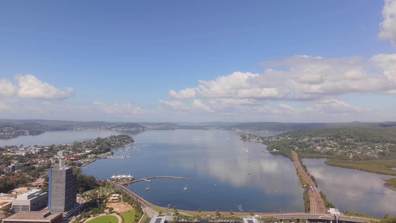 Aerial tilt down establishing of Polytech Stadium in Gosford surrounded by green field and distant coastline, Central Coast NSW Australia